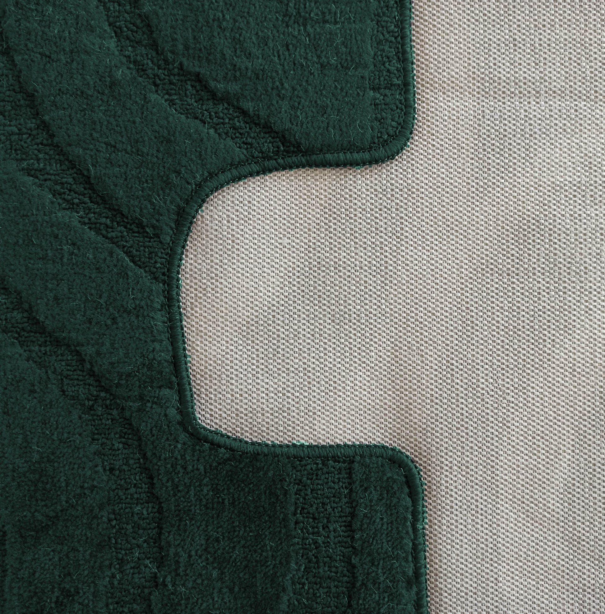 Tapis vert foncé à texture bouclée et motifs en relief, jouxtant un tissu beige clair tissé avec un bord incurvé prononcé