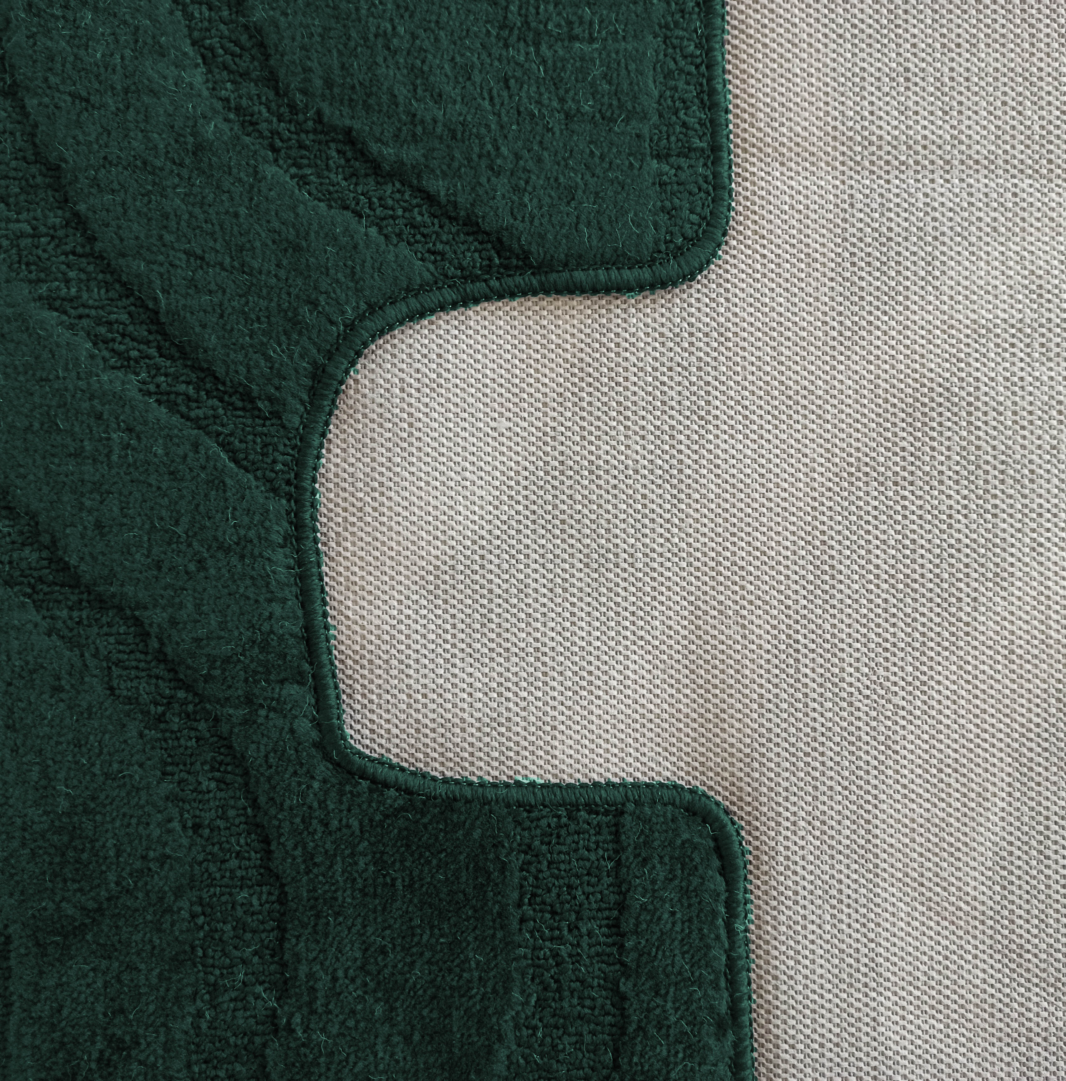 Tapis vert foncé à texture bouclée et motifs en relief, jouxtant un tissu beige clair tissé avec un bord incurvé prononcé