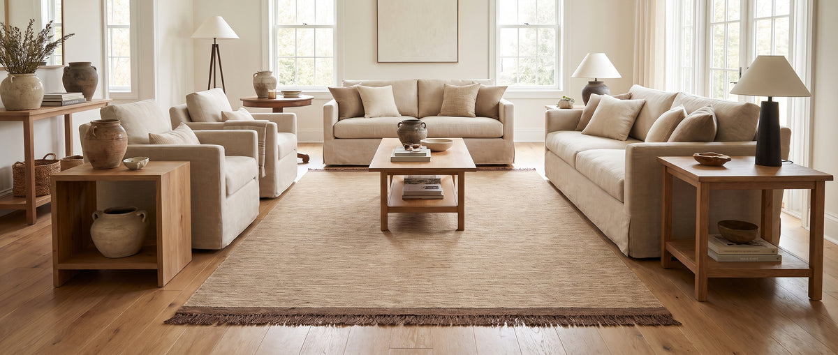Ce tapis rectangulaire en laine beige à la texture naturelle et franges marron, égaye un salon clair