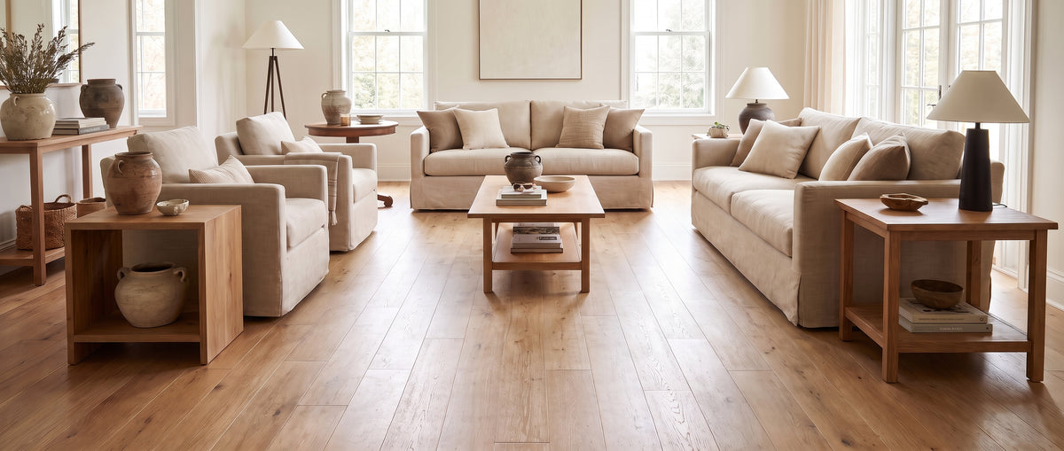 Sol en parquet clair d'un salon lumineux, avec des canapés beiges et du mobilier en bois naturel, sans tapis