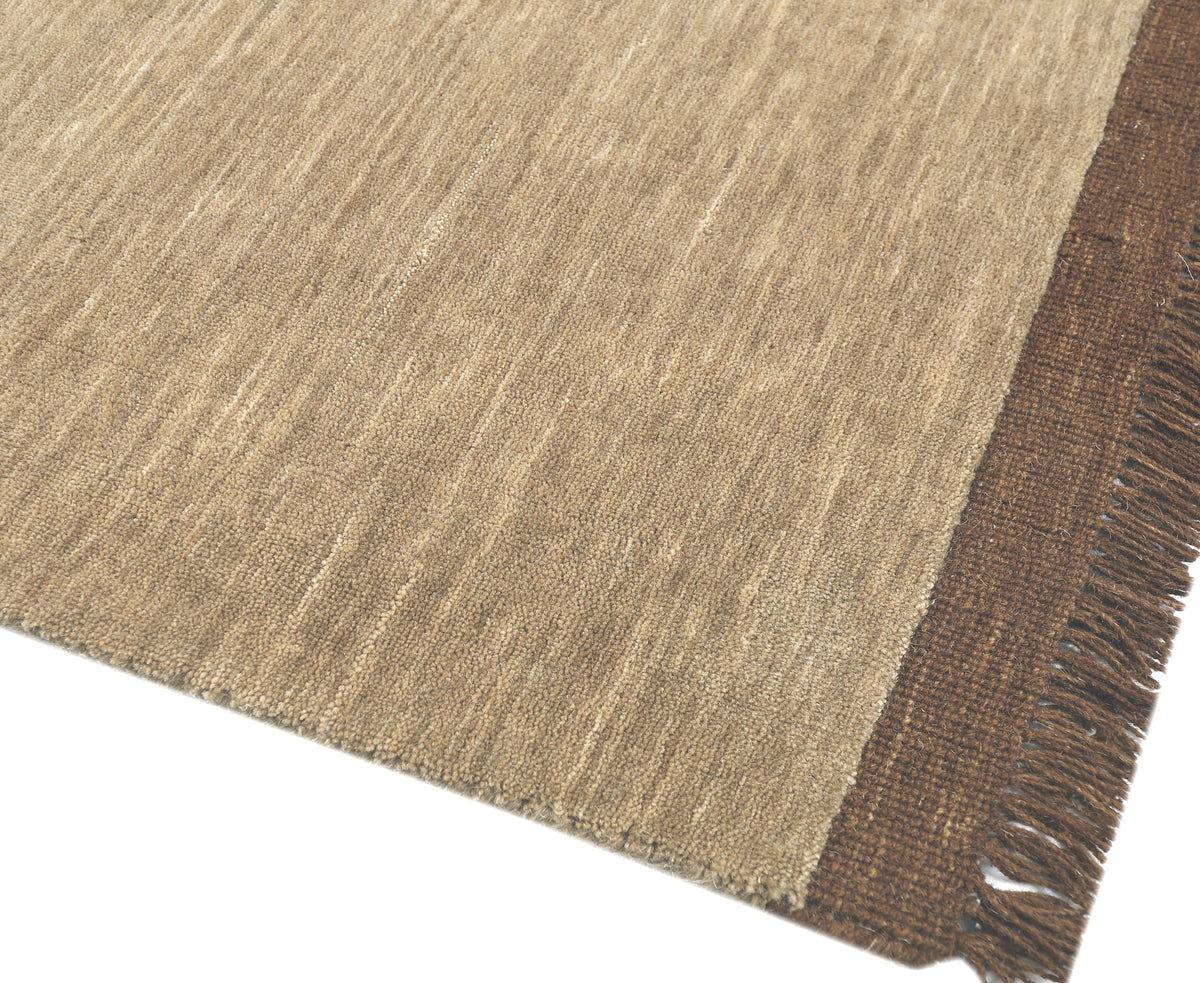 Fijne bruine franjes omzomen het getextureerde beige wollen weefsel