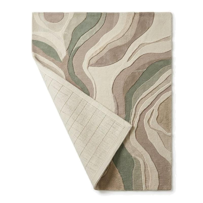 Coin replié du tapis en laine beige et vert sauge révélant l'envers tissé et l'épaisseur du relief sculpté