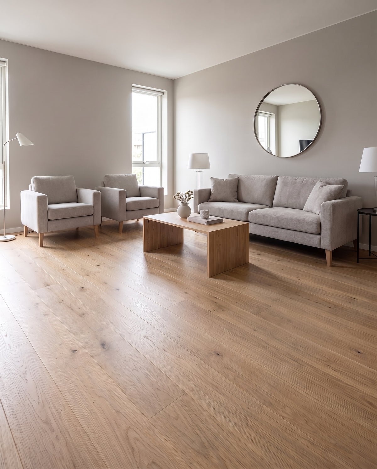 Dans ce salon lumineux au sol nu, un canapé, des fauteuils et une table basse en bois clair