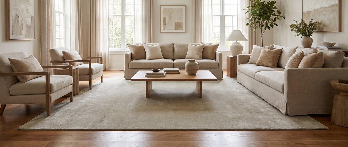 Rectangulaire et fait main, ce tapis en laine beige sable au toucher doux structure un salon clair