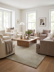 Un tapis fait main en laine beige sable réchauffe un salon clair de sa texture douce et unie