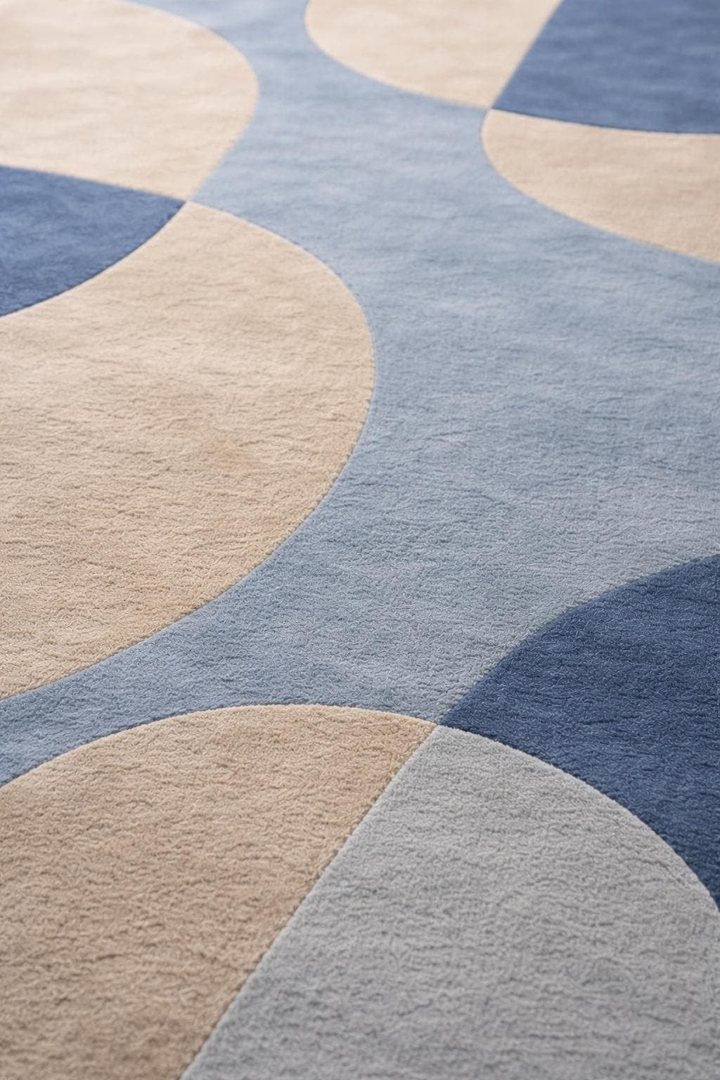 Gros plan sur un tapis en laine touffetée, aux courbes bleues et beiges, révélant la texture du velours coupé