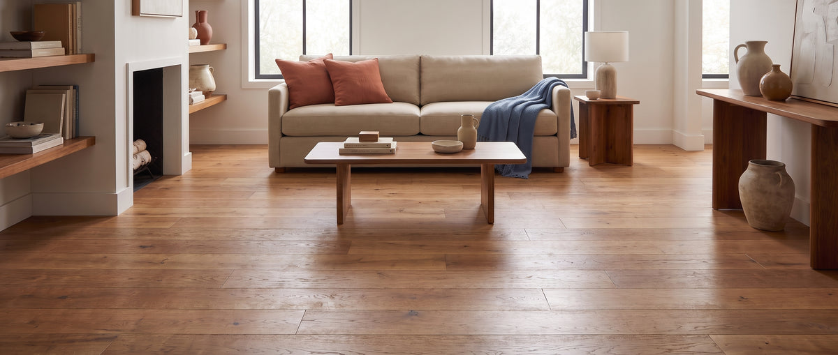 Dans ce salon élégant sans tapis, un canapé beige, des tables en bois et des objets décoratifs animent le parquet clair