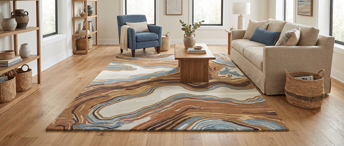 Un tapis rectangulaire en laine bouclée, aux motifs onduleux bruns, terracotta, crème et bleu, égaye un salon lumineux