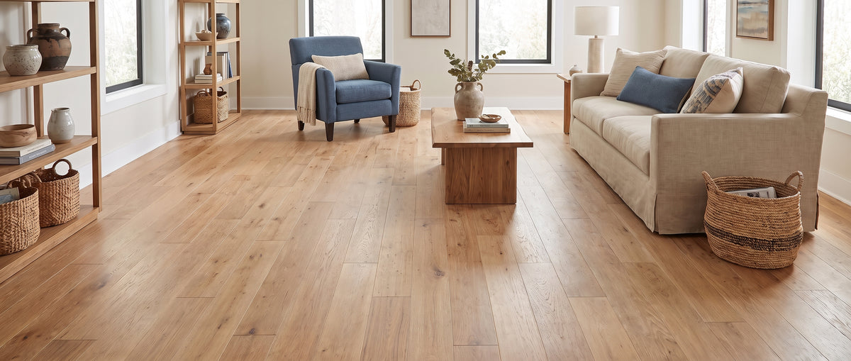 Pièce lumineuse aux murs blancs et parquet en bois clair, sans tapis au sol, avec canapé beige, fauteuil bleu et étagères