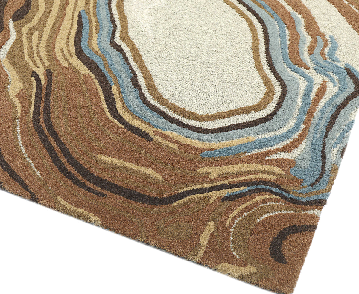 La texture bouclée de la laine terracotta, brune, crème et bleue révèle un motif aux reliefs doux