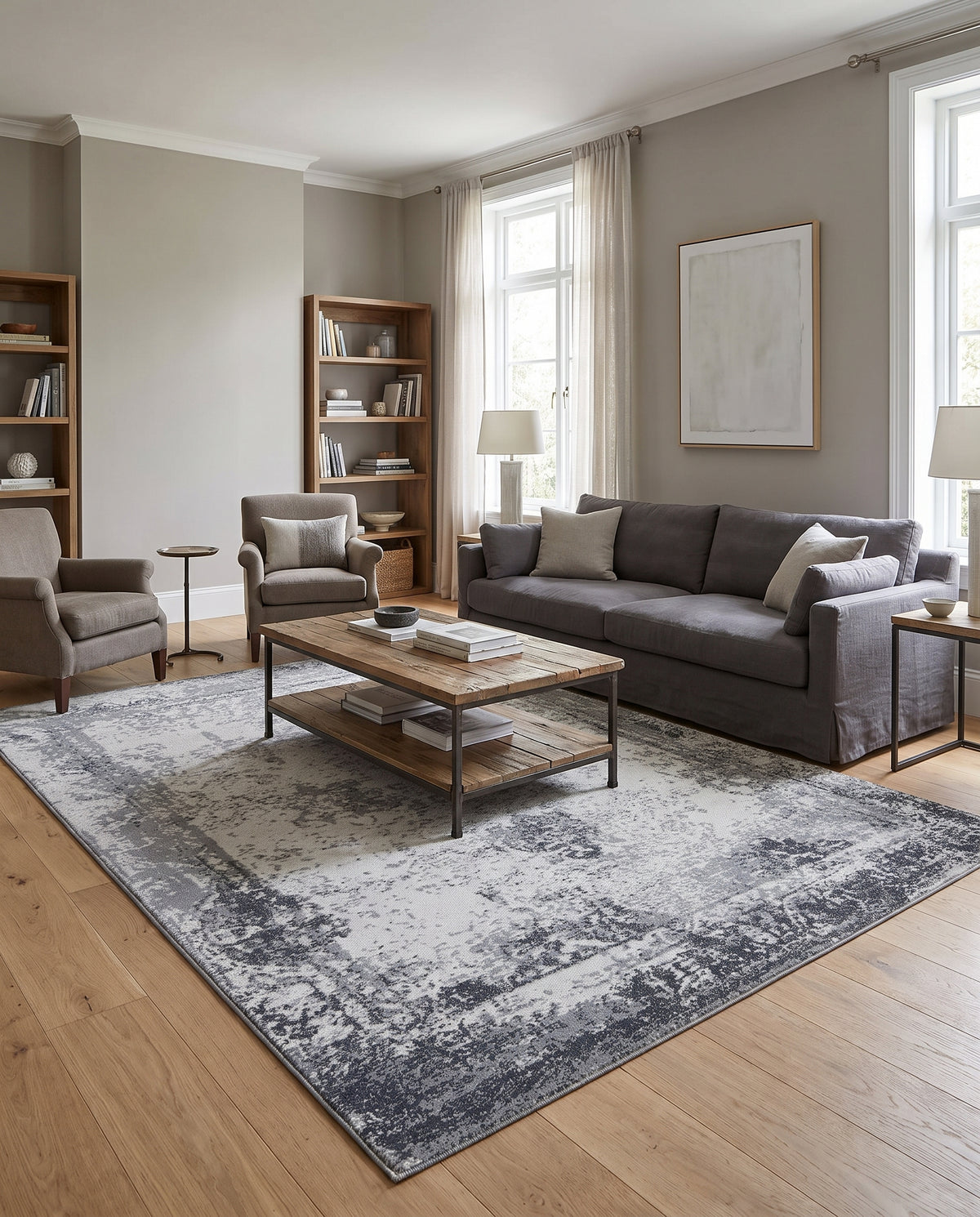 Dans un salon lumineux, un tapis rectangulaire en laine fait main, aux motifs abstraits gris et ivoire