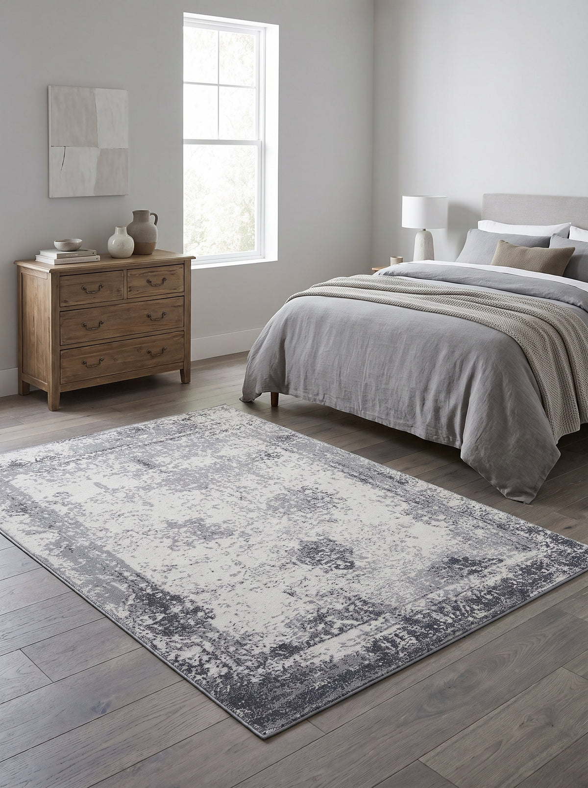 Des motifs abstraits gris et ivoire rehaussent ce tapis rectangulaire en laine fait main, au cœur d'une chambre lumineuse