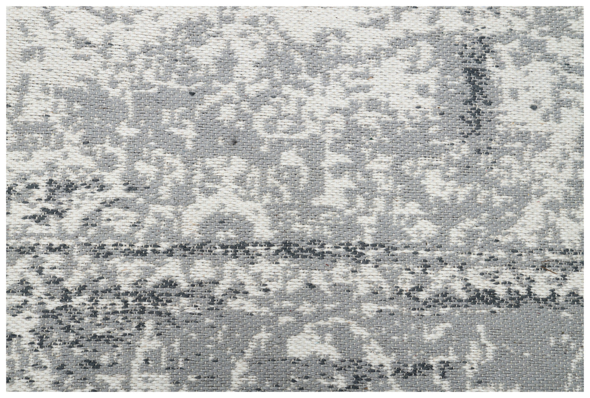 La texture tissée de la laine grise et ivoire révélant le motif abstrait du tapis fait main
