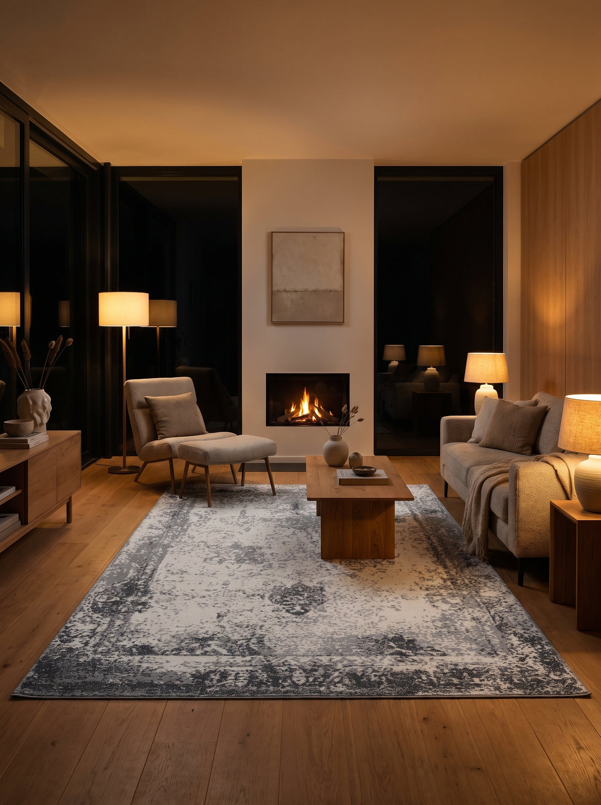 Un tapis en laine fait main, gris et ivoire, dévoile ses motifs abstraits et délavés dans un salon de nuit
