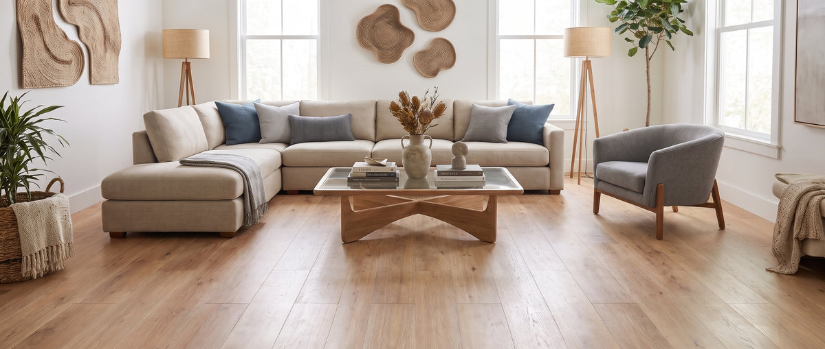 Pièce lumineuse sans tapis, le sol en bois clair accueille un canapé d'angle beige, un fauteuil gris et une table basse