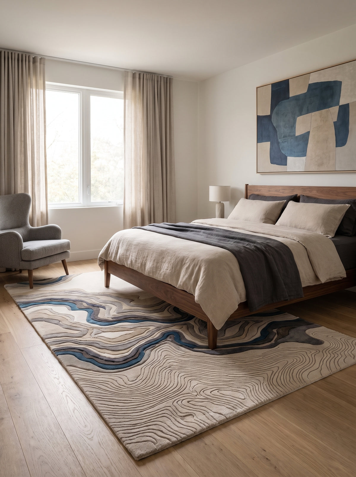 Dans une chambre moderne, un tapis rectangulaire en laine sculptée aux motifs ivoire, gris et bleu