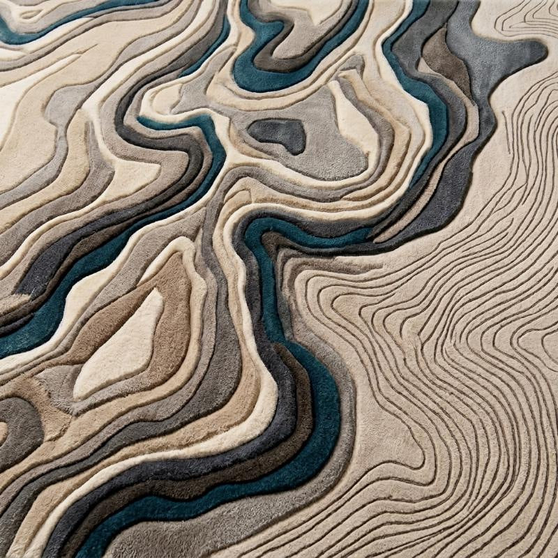 Motif détaillé de strates ondulantes en laine tuftée main, aux reliefs ivoire, gris et bleu pétrole, avec lignes fines