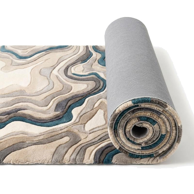 L'envers gris du tapis en laine tuftée et les strates ivoire, beiges, grises et bleues de son motif en relief