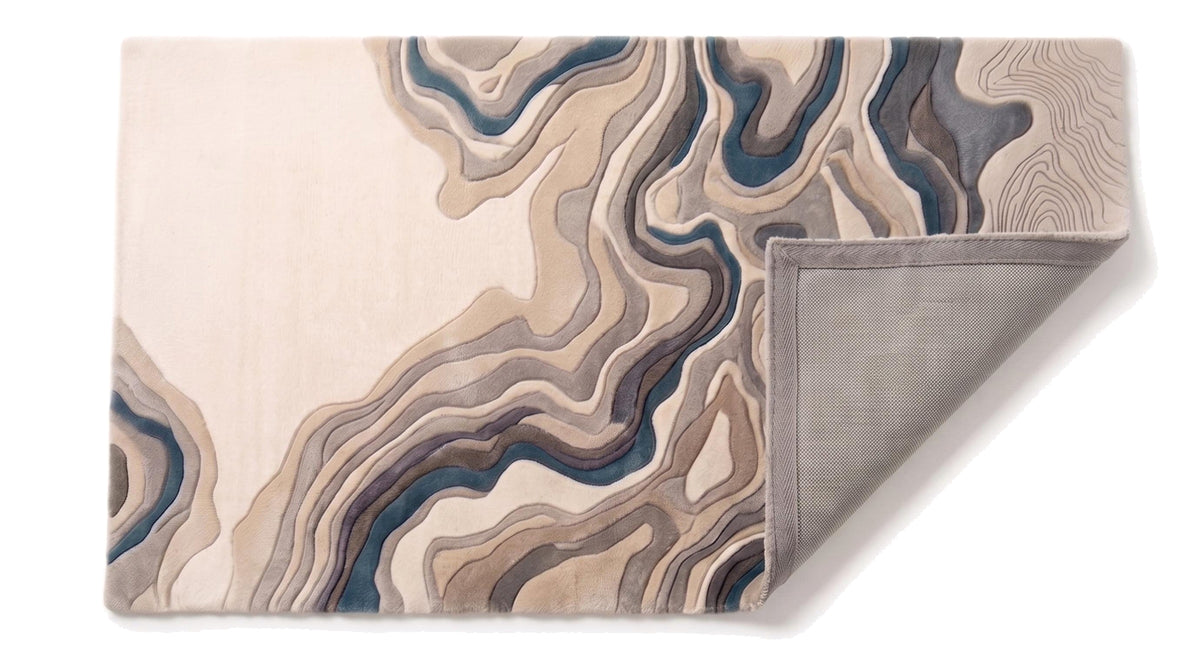 Les strates ondulantes et les fines lignes du motif en relief, ainsi que l'envers gris du tapis en laine