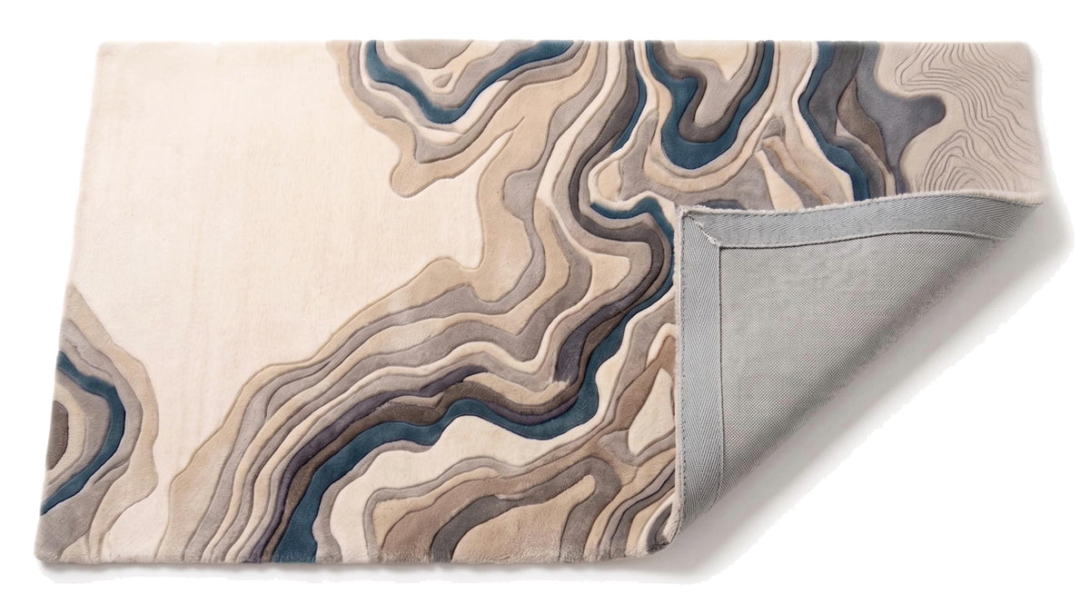 Détail des strates de laine aux couleurs ivoire, beige, grise et bleue et envers gris du tapis sculpté