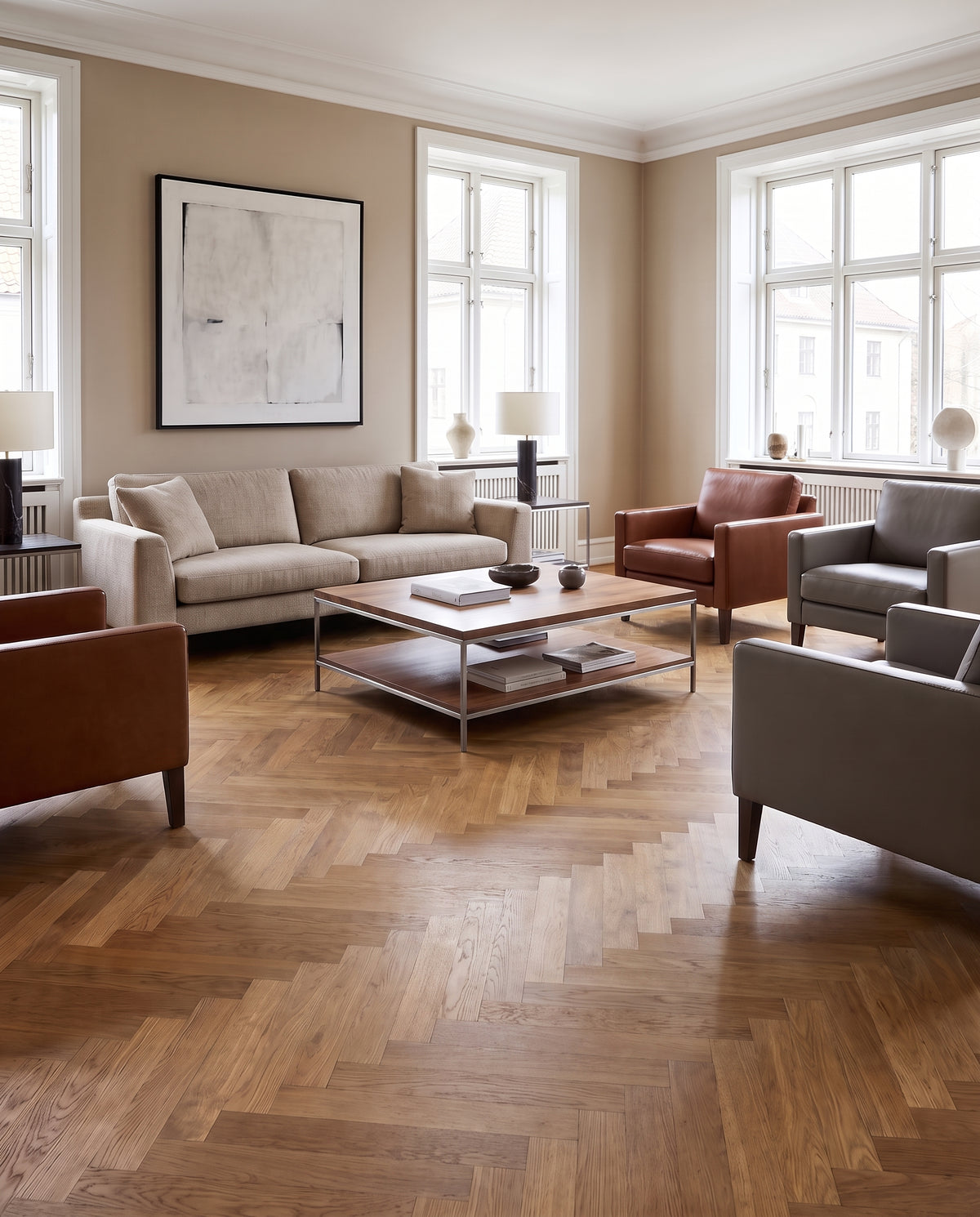 Scène de salon élégant avec murs clairs, parquet chevron nu, canapé beige et fauteuils en cuir, sans tapis visible
