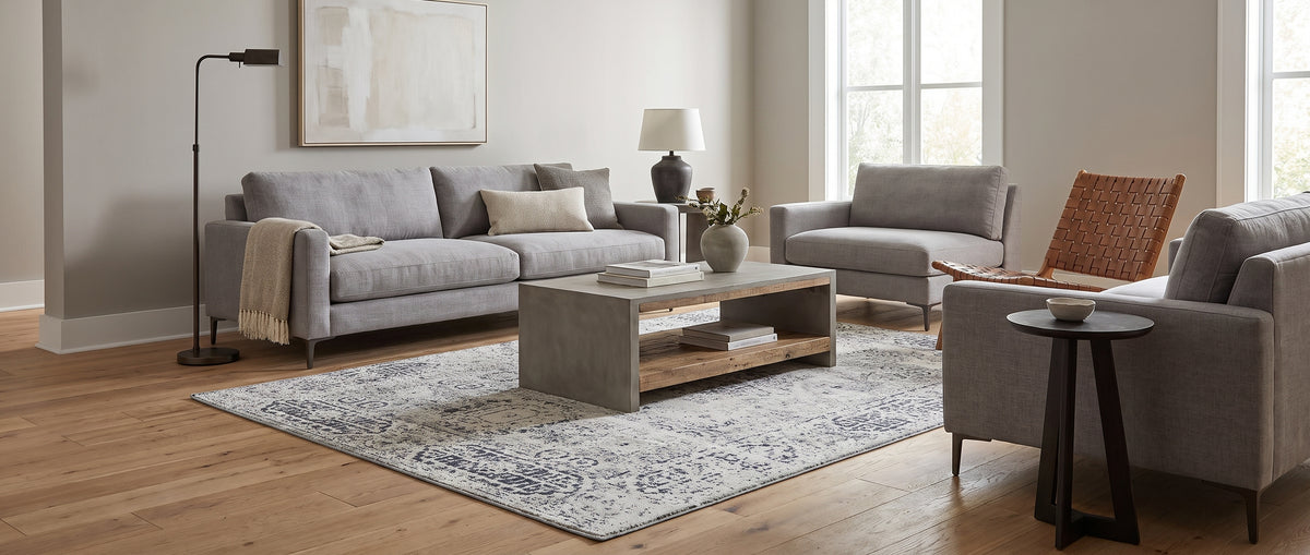 Laine ivoire et grise, ce tapis rectangulaire fait main aux motifs délavés habille un salon lumineux