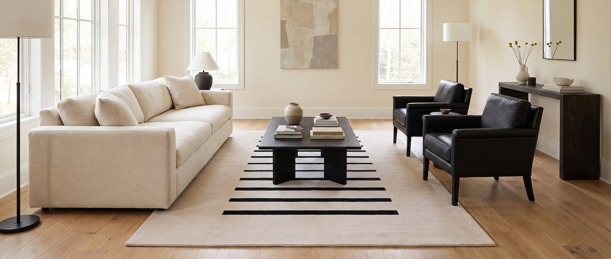 Laine ivoire et ses bandes noires asymétriques habillent un salon moderne, sous une table basse sombre