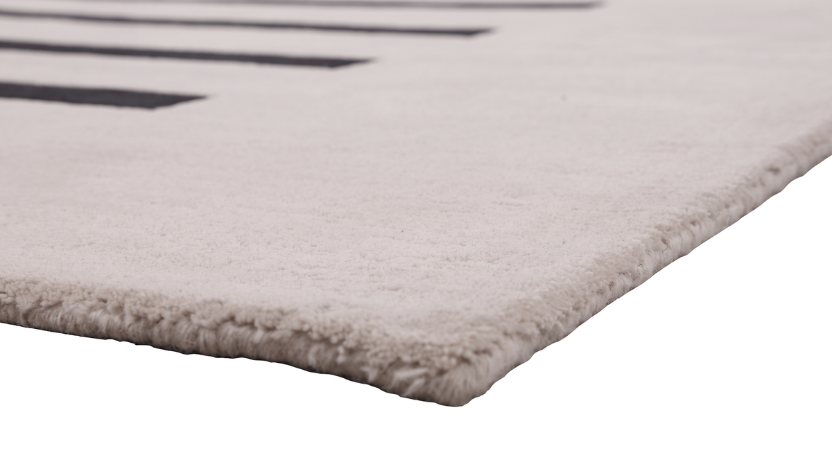 L'épaisseur et le bord soigné d'un tapis en laine ivoire fait main, montrant sa texture riche