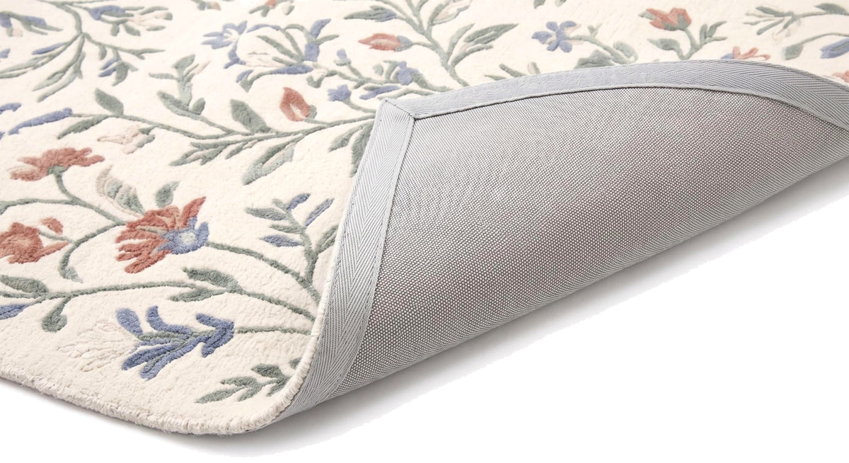 Motifs floraux en relief sur laine ivoire à poil coupé, avec un coin replié montrant l'envers gris