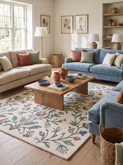 Au sol d'un salon, un tapis en laine ivoire à poil coupé arbore des motifs floraux ramifiés aux couleurs douces