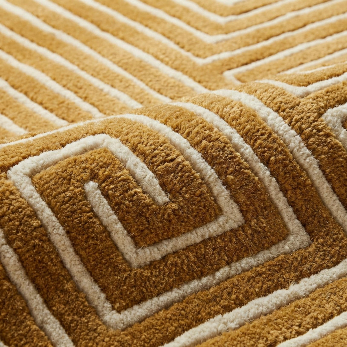 Le pli du tapis en laine ocre tuftée met en valeur le relief et la texture épaisse du motif labyrinthique ivoire