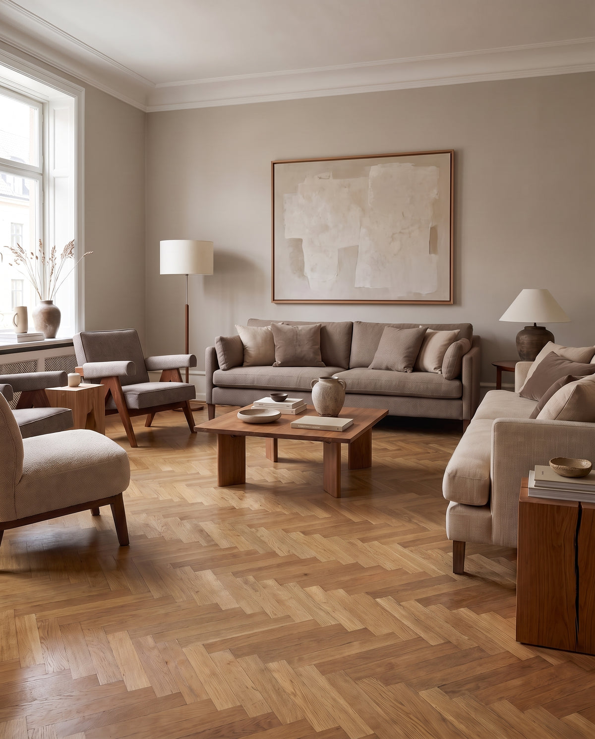 Ambiance lumineuse d'un salon sans tapis, au parquet chevrons, meubles clairs et tableau abstrait