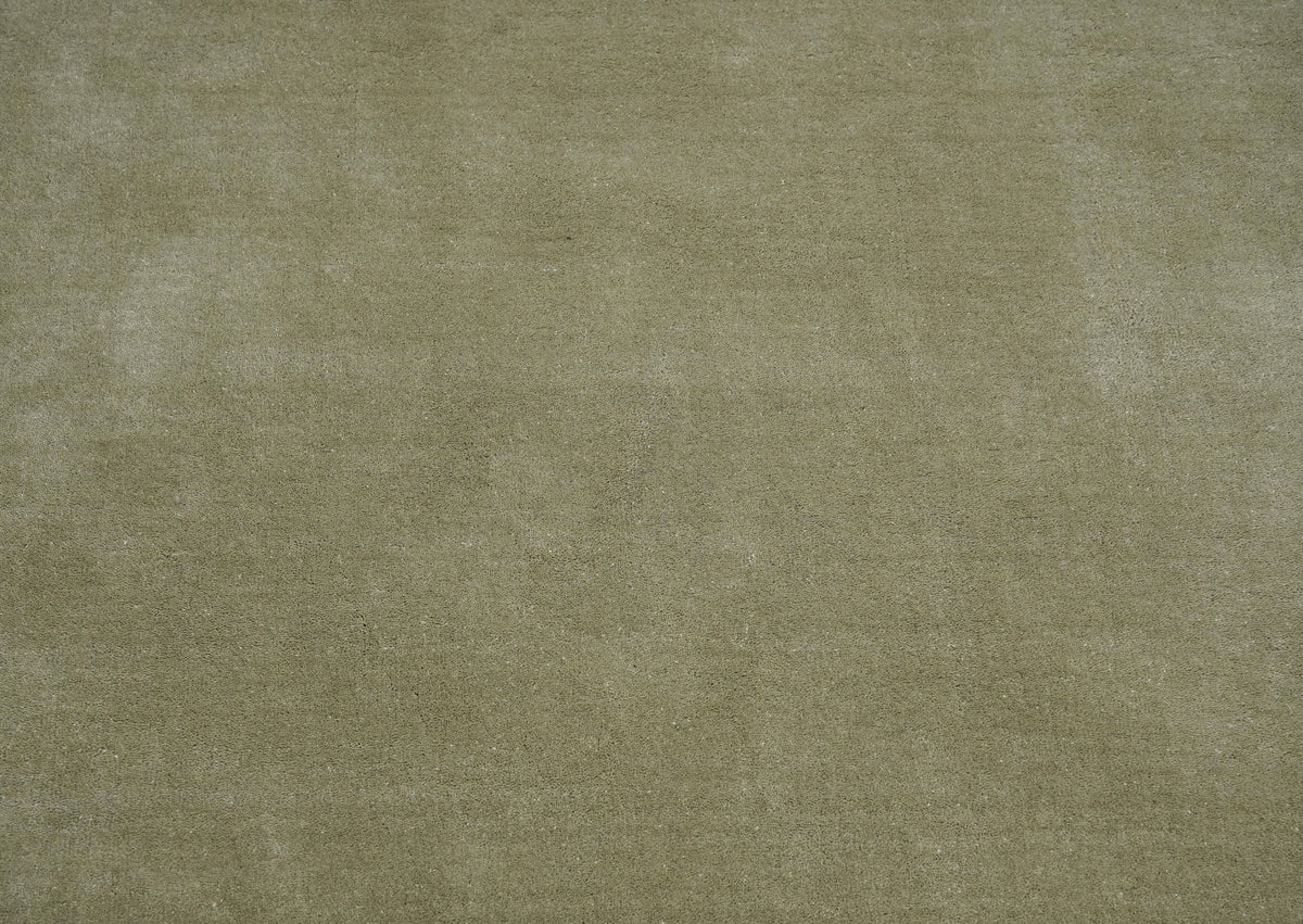 Gros plan sur le relief et la matière douce d'un tapis en laine taupe fait main, aux fibres nuancées