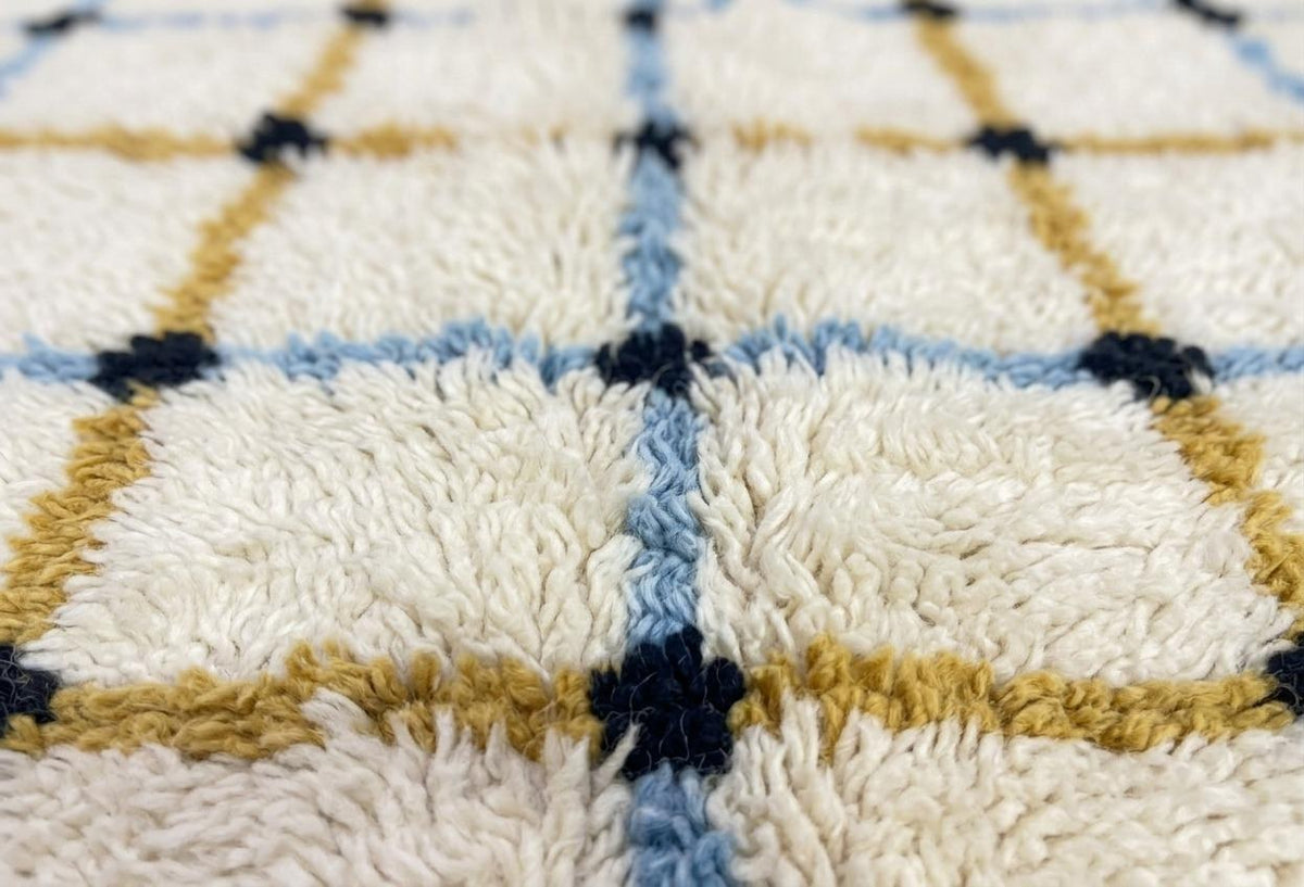 Gros plan sur la laine du tapis berbère Tafrin, poil blanc et moutarde noué à la main