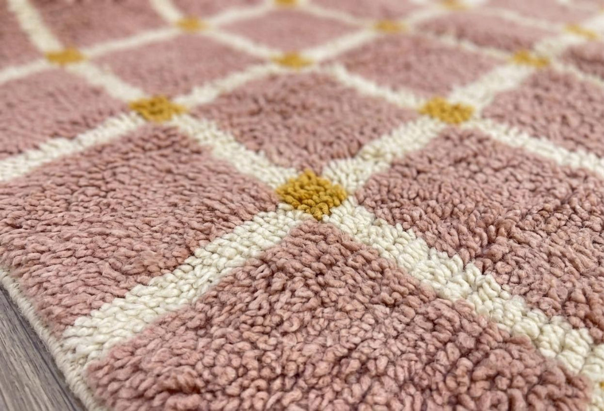 Gros plan sur la laine du tapis berbère Tizwira, poil rose poudré noué à la main