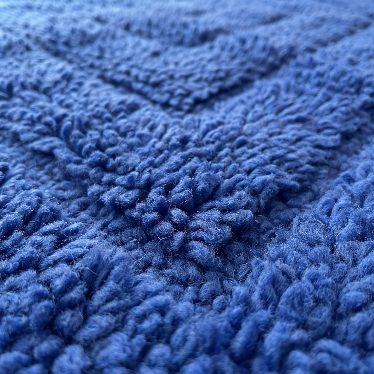 Gros plan sur un motif du tapis berbère Tirelwa, bleu cobalt uni à poil dense