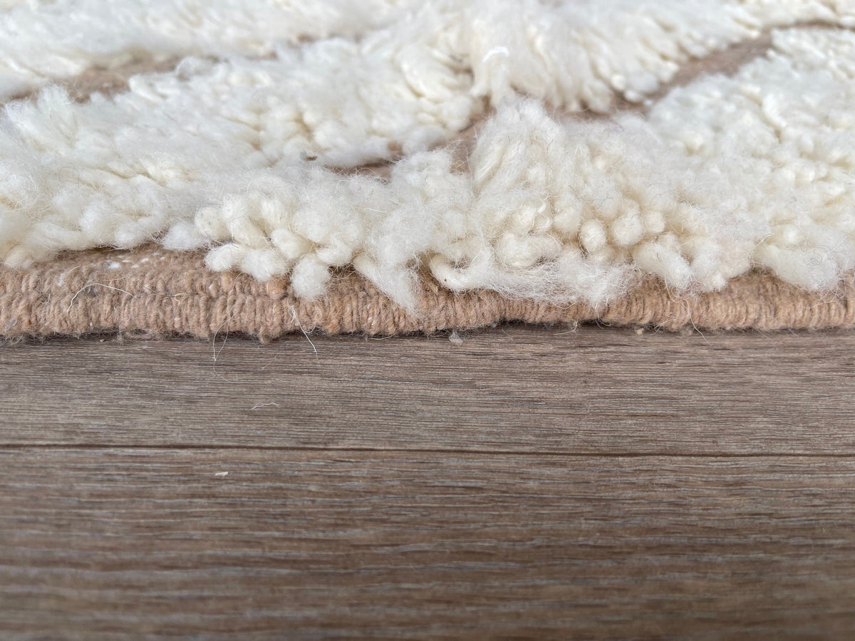 Gros plan sur le coin relevé du tapis berbère Amtoudi, bordure et envers visibles de près