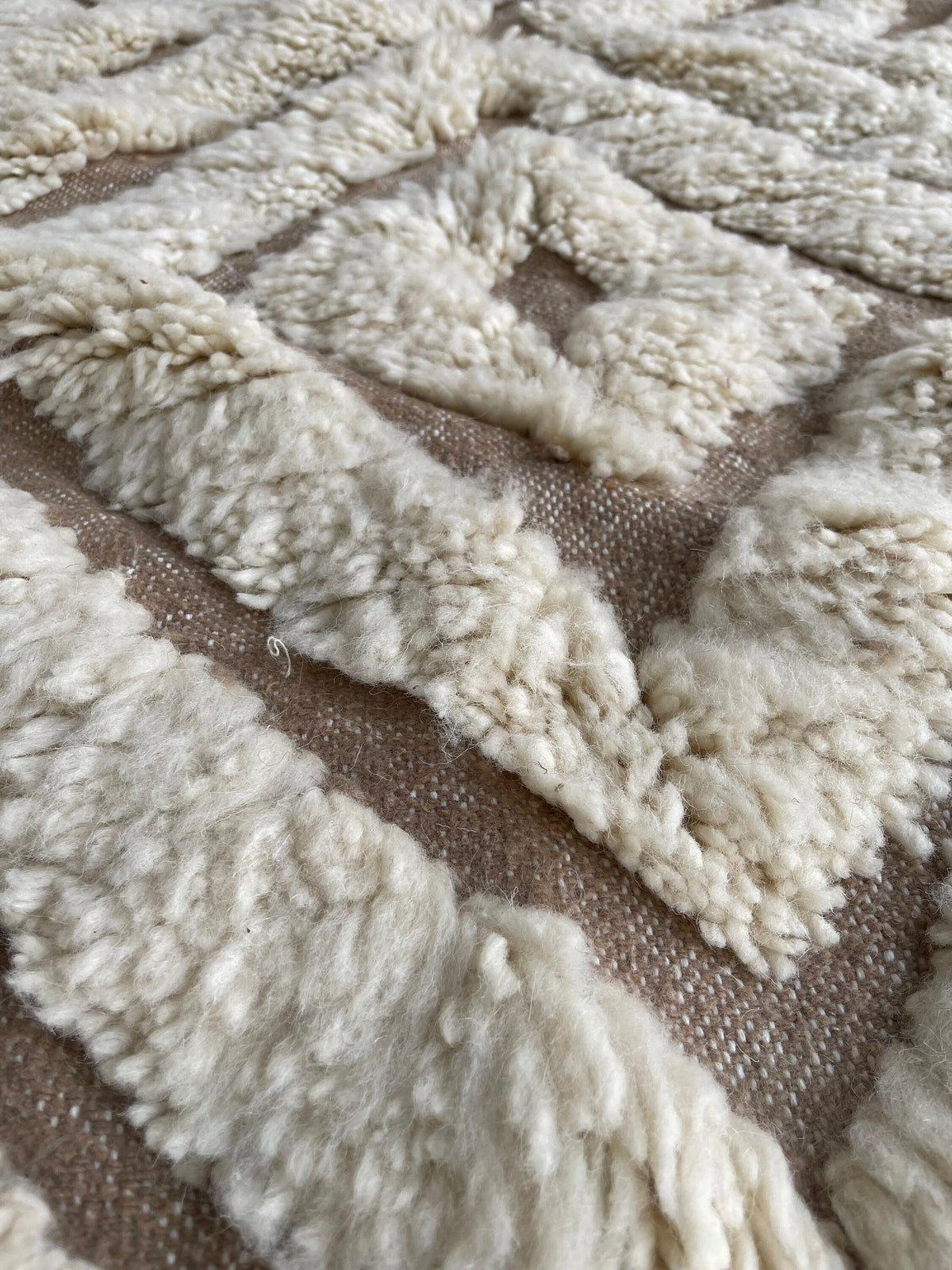 Gros plan sur la laine du tapis berbère Amtoudi, laine de mouton au poil long, blanche et beige
