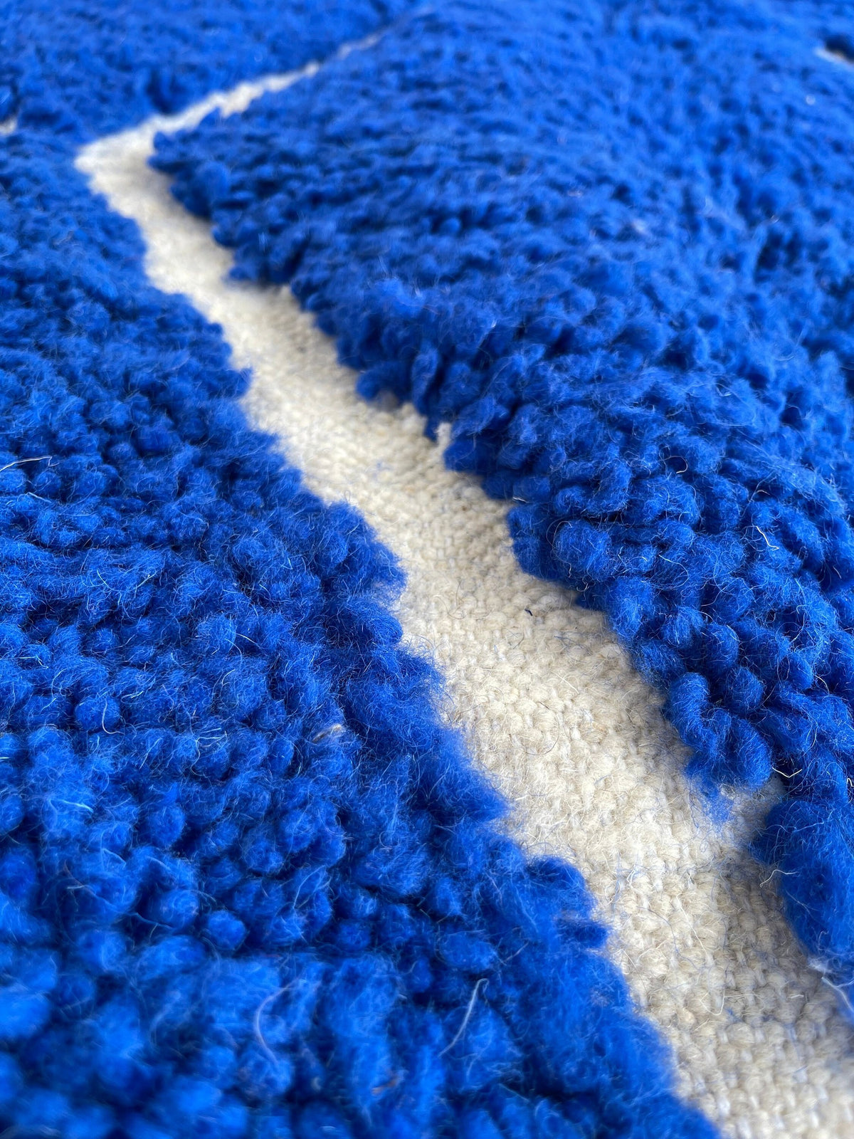 Gros plan sur la laine du tapis berbère Asigna, laine de mouton au poil long, bleu roi