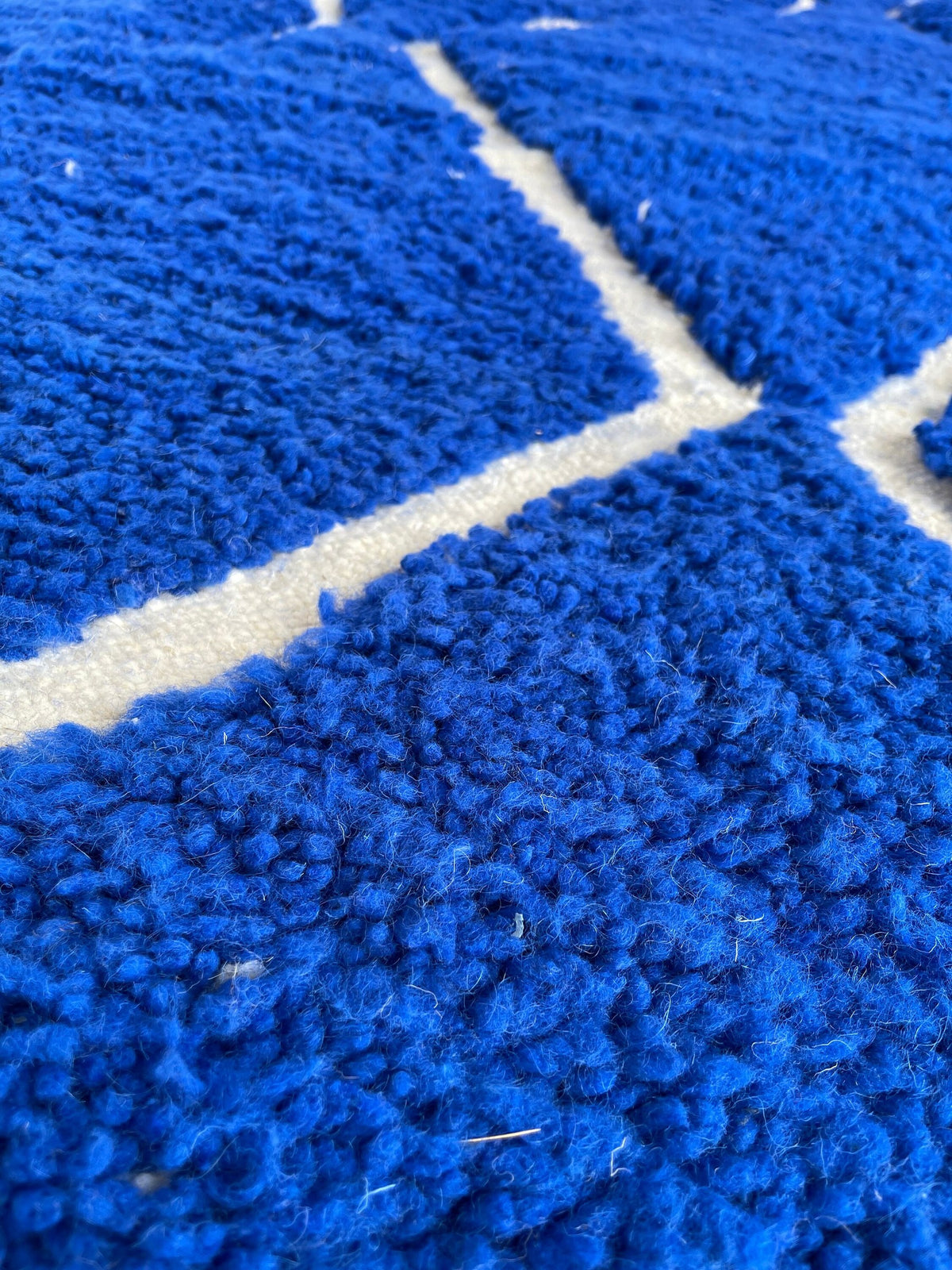 Gros plan sur la laine du tapis berbère Asigna, nœuds serrés et tracé du motif de près