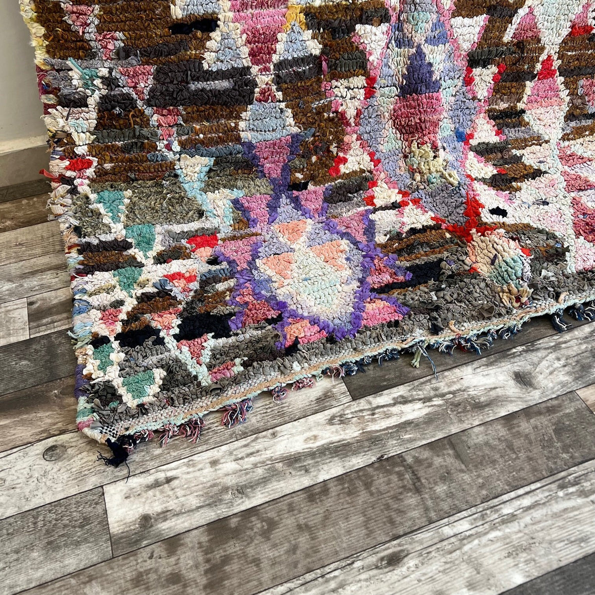 Gros plan sur le coin relevé du tapis berbère Aberkan, bordure et envers visibles de près