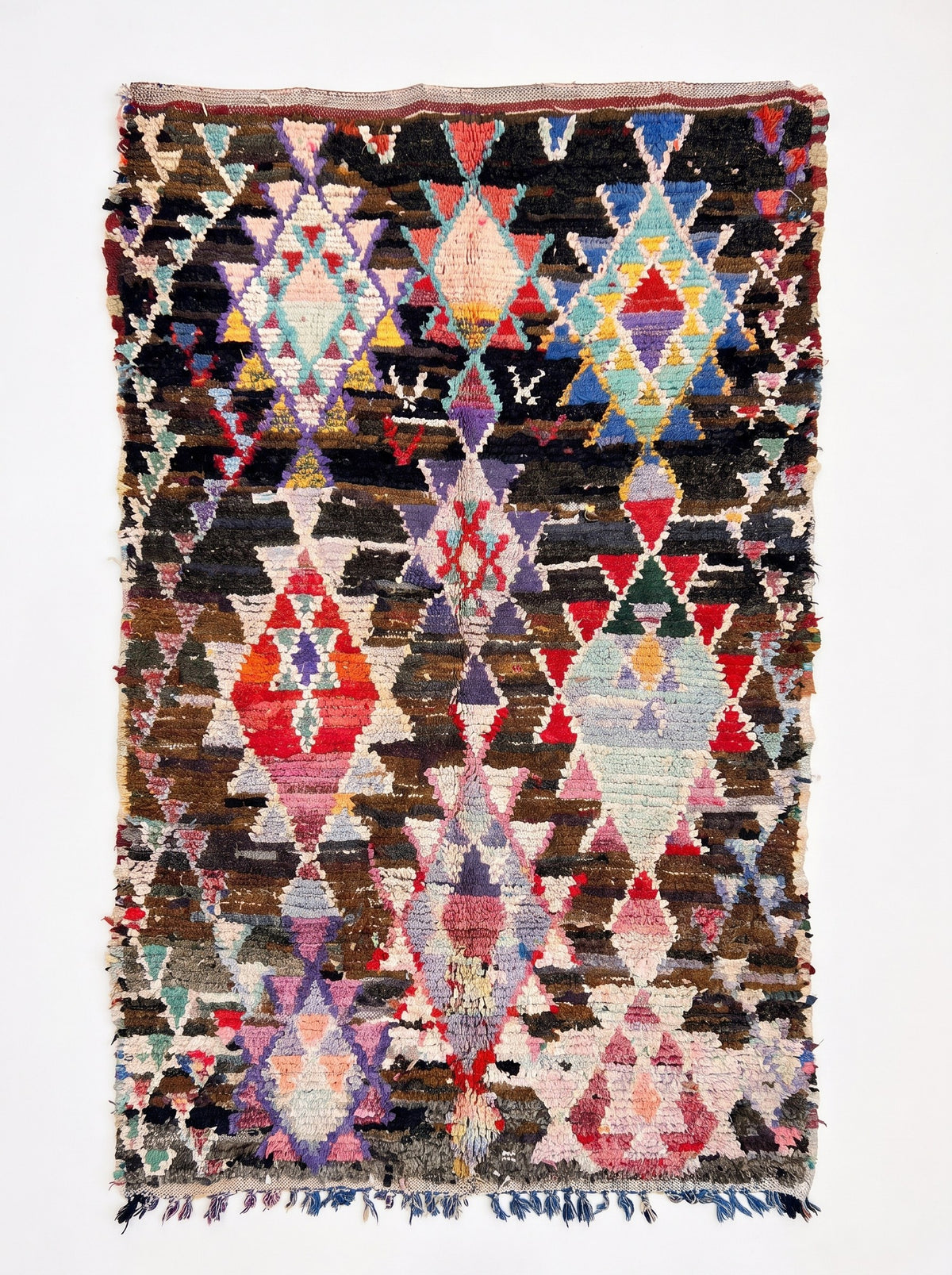 Tapis berbère à losanges brun multicolore Aberkan vu à plat, fond brun foncé, en haut trois grands losanges rose