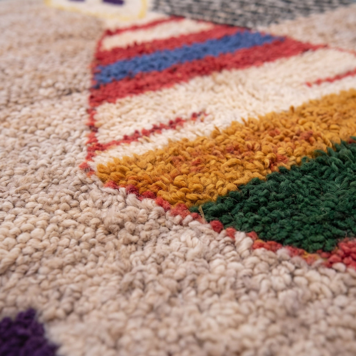 Gros plan sur un motif du tapis berbère Ahaggar, fond beige, bords en damier, en haut losange