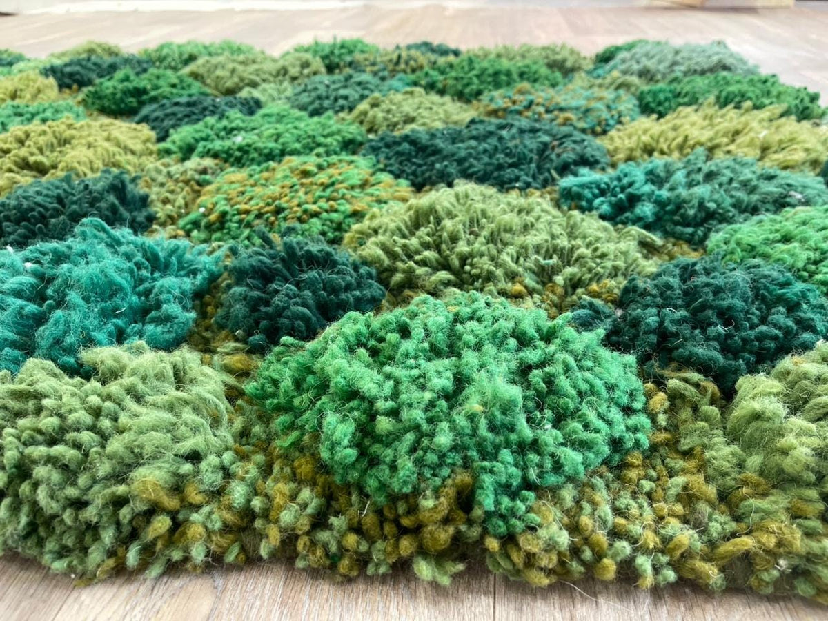 Gros plan sur la laine du tapis berbère Zinat, laine de mouton au poil long, vert mousse