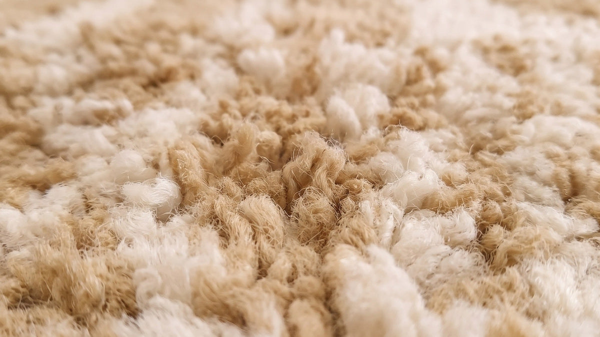Gros plan sur la laine du tapis berbère Tanezruft, poil beige noué à la main