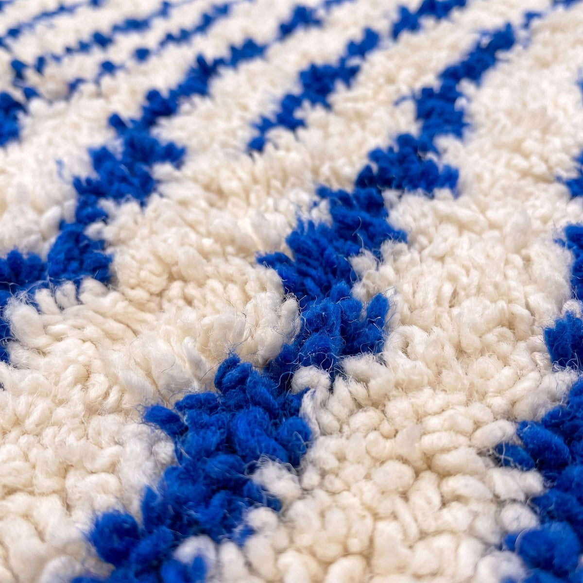 Gros plan sur un motif du tapis berbère Ageffur, fond écru à poil long, une quinzaine