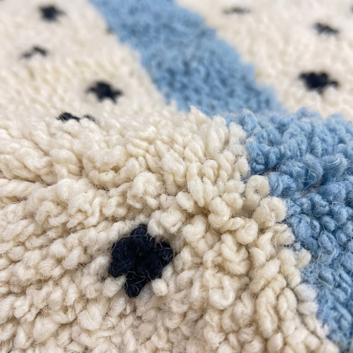 Gros plan sur un motif du tapis berbère Tadmil, champ à poil long, fond ivoire