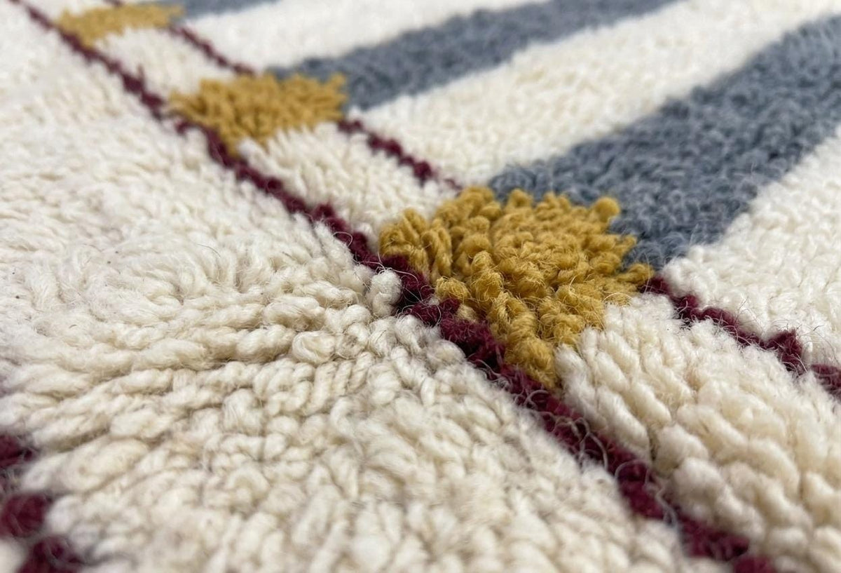 Gros plan sur la laine du tapis berbère Adlis, nœuds serrés et tracé du motif de près