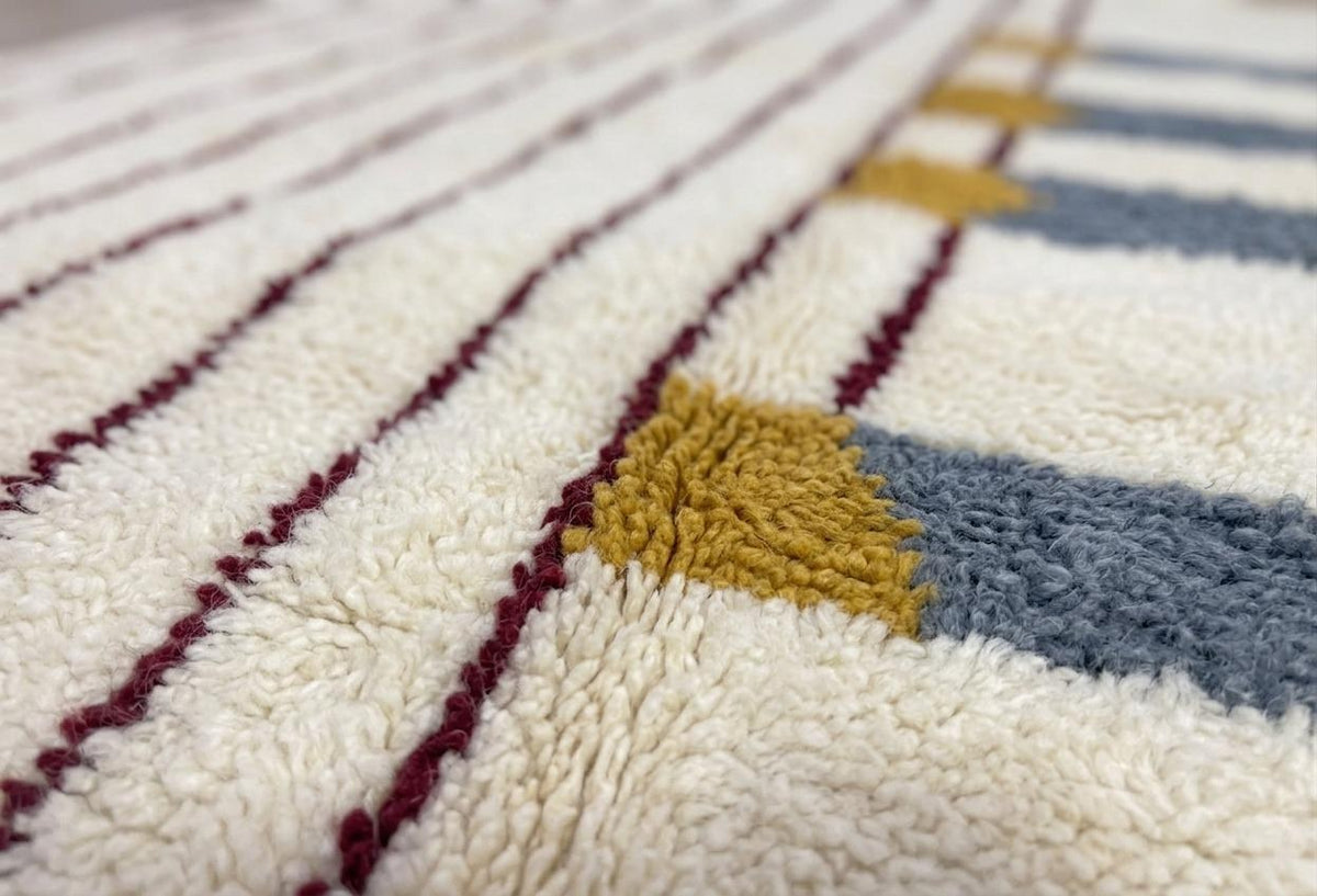 Gros plan sur la laine du tapis berbère Adlis, poil blanc et gris noué à la main