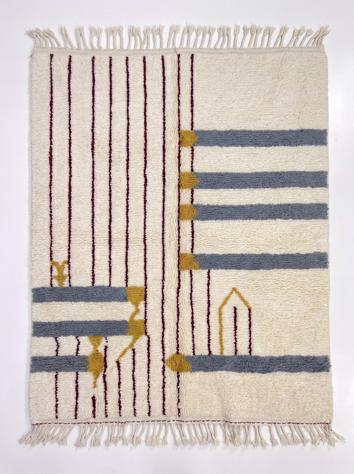 Tapis berbère à rayures blanc et gris Adlis vu à plat, fond écru, à gauche huit fines lignes verticales bordeaux, franges écrues